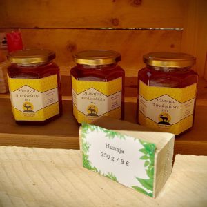 Kolme purkkia hunajaa, joissa lukee "Hunajaa Airakselasta 350 g." Edessä hintalappu, jossa lukee "9 euroa".