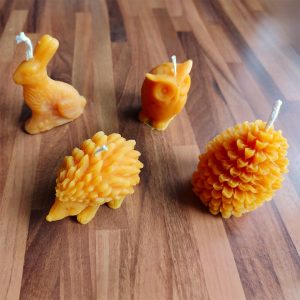 Useita keltaisia mehiläisvahakynttilöitä. Kuvassa kynttilöitä, joita valettu muotoihin siili, pöllö, jänis ja käpy.