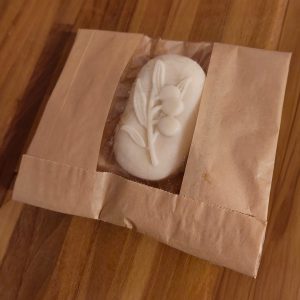 Valkoinen koristeellinen saippuapala pakattuna paperiseen pussiin.